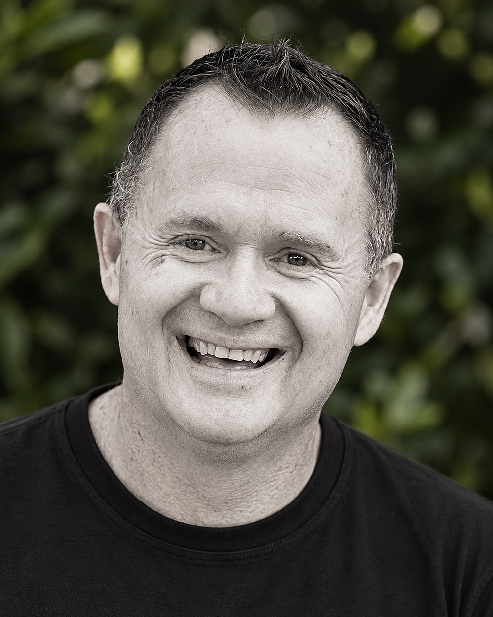 Andrew Mooney of Elevate Landscapes Queensland, smiling in front of garden greenery
